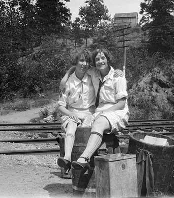 Elsie Stephens and unknown girl standing in wooden barrel near railroad at Camp H ighland, 1920s.